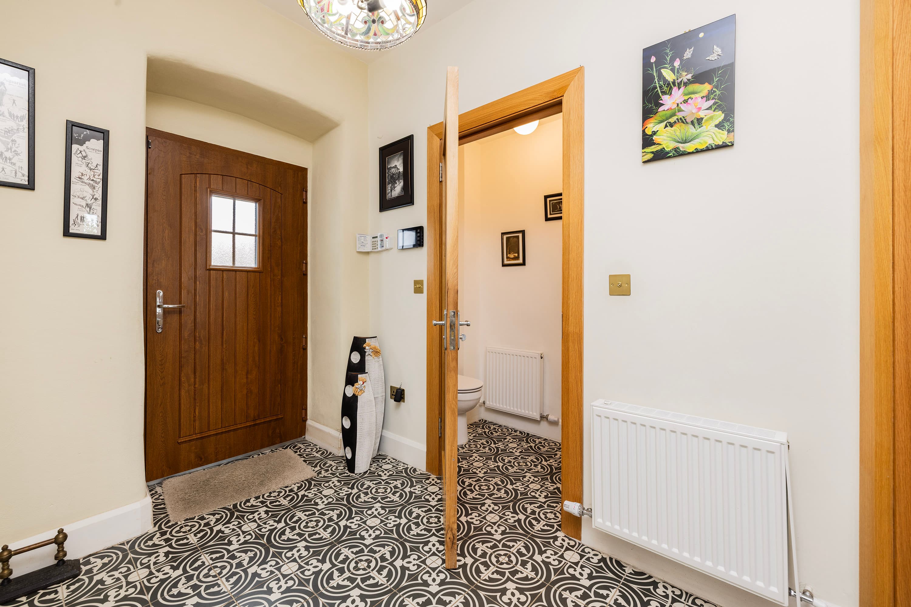 Entrance hallway with patterned tiled floor and guest WC