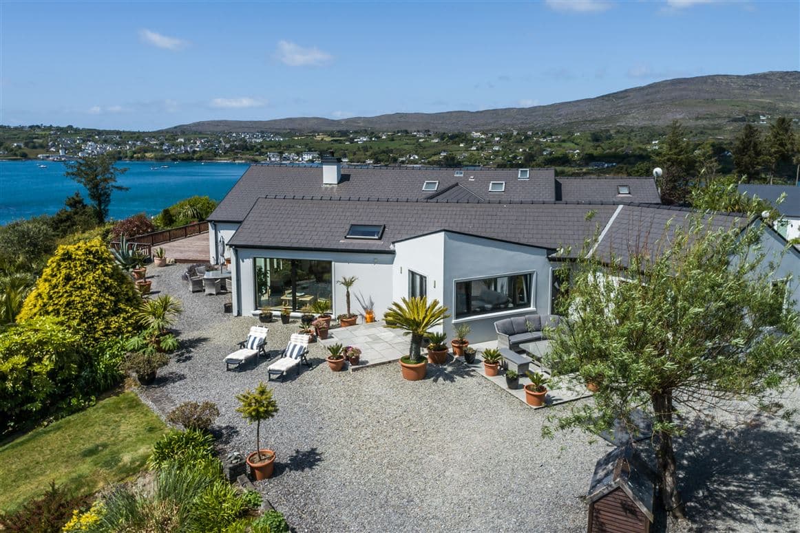 Aerial view of the outdoor terrace with palms, seating and Schull Harbour in the background