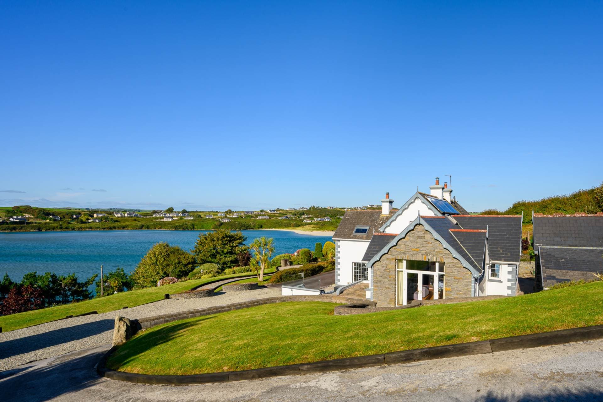 Stone-fronted gable of the house with solar panels and views over the beach