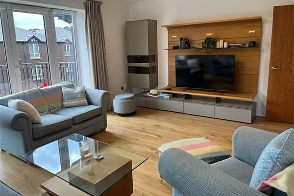 Open-plan living area with sofas, wall-mounted TV unit and balcony access